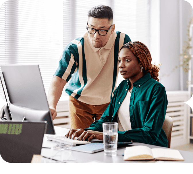 Two colleagues looking intently at a computer screen.